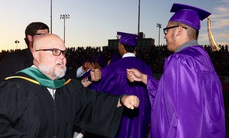 Teacher Howard Clarke fist bumps a student at graduation.